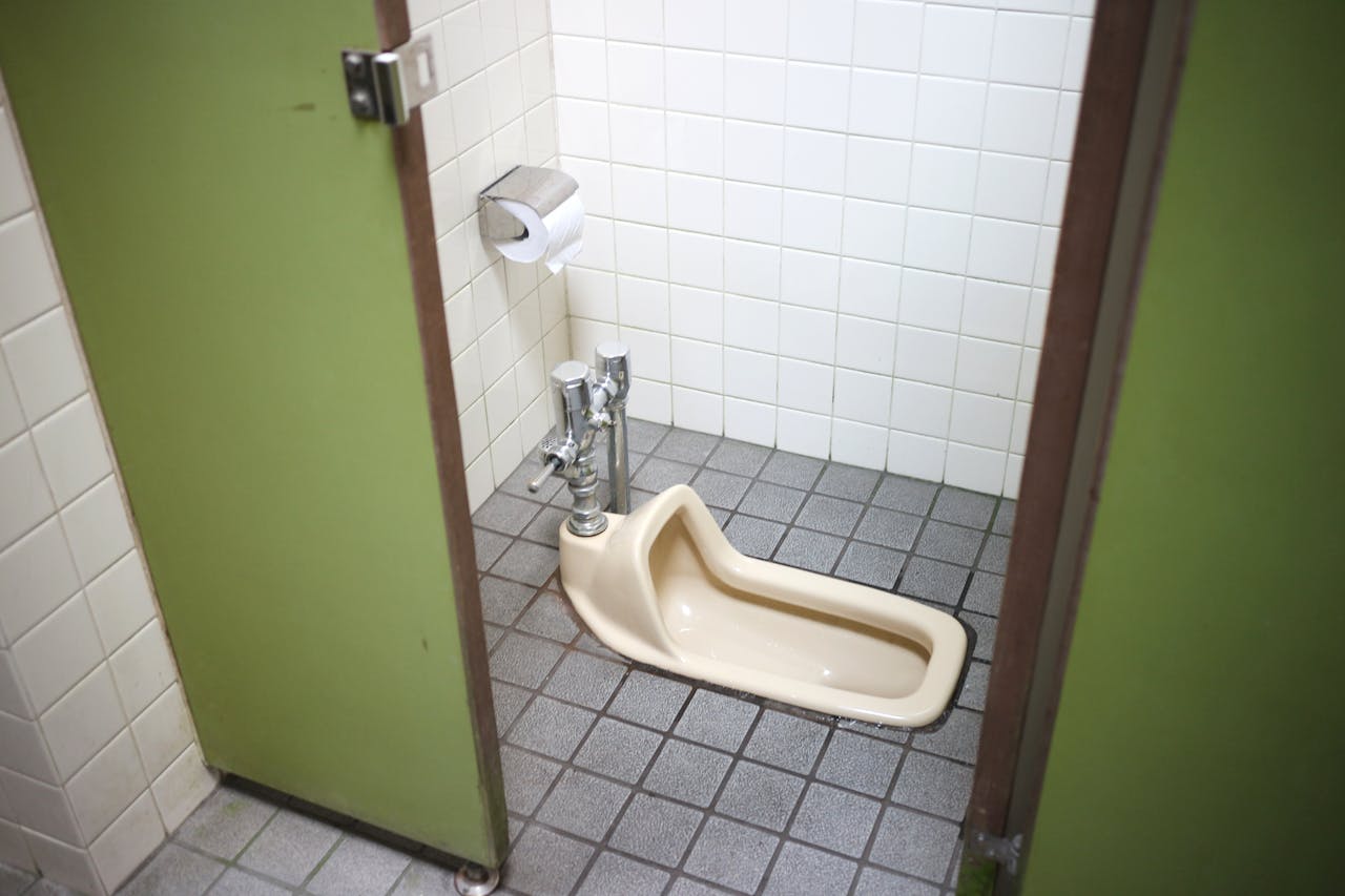 Image of a squat toilet in a public restroom with tiled walls and floor.